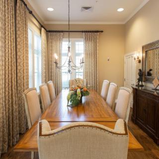 A well-decorated dining room with a long wooden table and upholstered chairs.