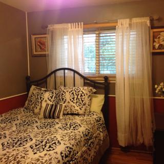 A cozy bedroom with decorative bedding and sheer curtains on the window.