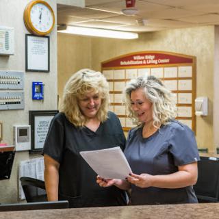 Two healthcare staff members collaborating at the reception desk.