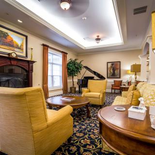 A cozy living room with plush furniture, a piano, and warm lighting.