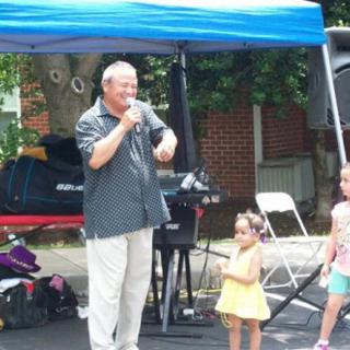 A performer entertains children at an outdoor event under a tent.