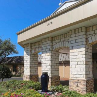 A stone building with columns and a landscaped garden in the foreground.