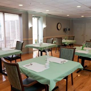 A well-lit indoor dining area with tables and chairs covered in green tablecloths.