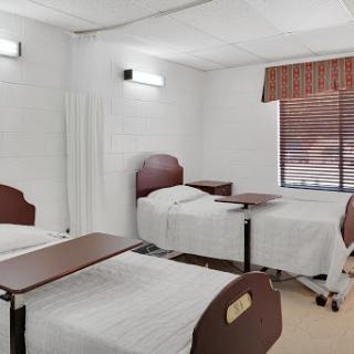 A clean and organized hospital patient room featuring multiple beds.