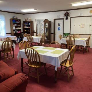 A cozy dining area with tables and chairs, surrounded by bookshelves and decorations.