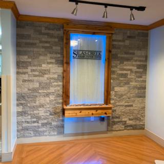 A stylish interior corner featuring a stone wall, wooden elements, and ambient lighting.