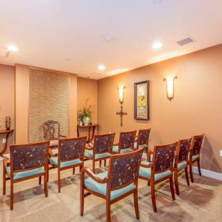 A small chapel interior with neatly arranged chairs facing an altar.