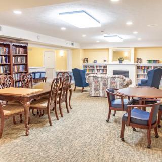 A cozy library interior with wooden tables and chairs, surrounded by bookshelves.