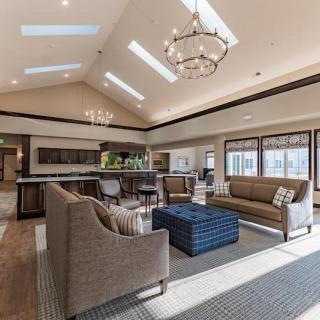 A spacious and modern living room with elegant furniture, skylights, and a large chandelier.