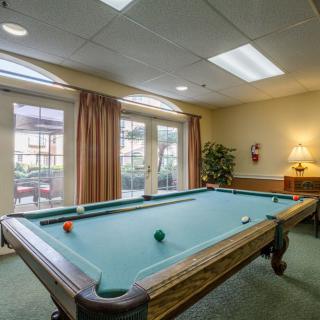 A cozy game room featuring a billiards table with natural light streaming through large windows.