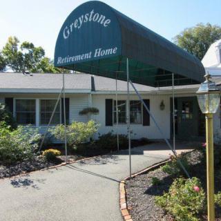 Entrance of a funeral home with a green awning labeled 'Greystone'.