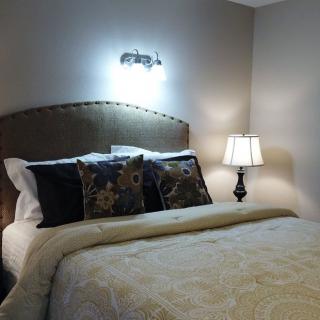 A cozy bedroom with a well-decorated bed and ambient lighting.