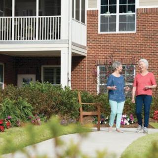 Two elderly women enjoying a leisurely walk in their community garden.