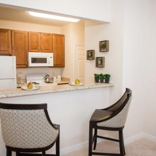A modern kitchen with a bar counter and two bar stools.