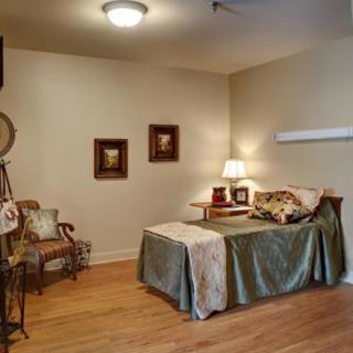 A cozy bedroom with a neatly made bed, wooden flooring, and stylish decor.