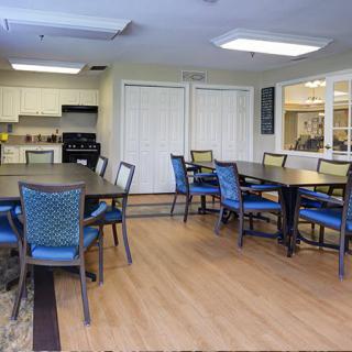 A modern dining area with tables and chairs, adjacent to a kitchen.