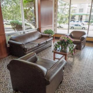 A cozy lobby area with leather sofas, armchairs, and a coffee table near large windows.