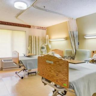 A clean and well-lit hospital room with two patient beds and medical equipment.