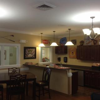 A cozy kitchen and dining area with a bar counter, wooden cabinets, and various lighting fixtures.