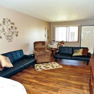 A cozy living room with modern furnishings, featuring two black sofas, a recliner, and hardwood flooring.