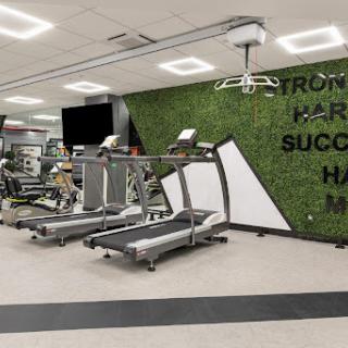 A modern indoor gym featuring treadmill machines and a vibrant green wall.