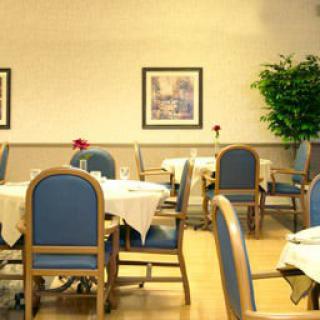 An indoor dining area with tables and chairs, decorated with wall art and plants.