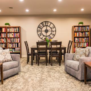 A cozy and modern living space featuring a dining area, bookshelves filled with books, and comfortable seating.