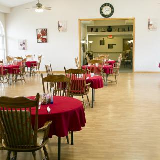 An empty restaurant dining room with tables covered in red tablecloths.