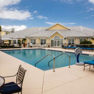 A residential swimming pool area with lounge chairs on a sunny day.