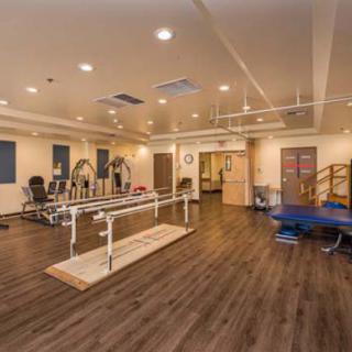 A spacious therapy center equipped with exercise machines and rehabilitation tools.
