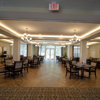 A spacious and elegant dining area with multiple tables and chairs arranged symmetrically under warm lighting.