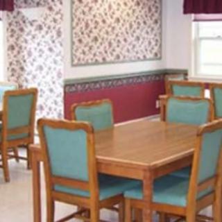 A dining area with wooden tables and teal upholstered chairs, accented by floral wallpaper.