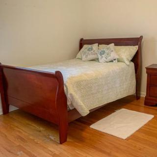 A cozy bedroom with a wooden sleigh bed and matching nightstand.