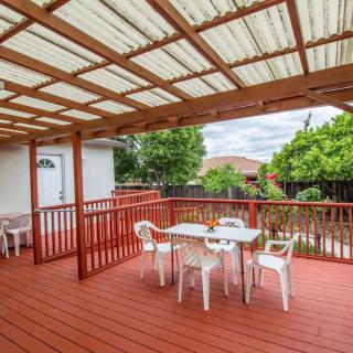 A spacious wooden deck with a pergola, featuring outdoor seating and surrounded by greenery.