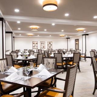 An elegant dining area with neatly arranged tables and chairs, set in a warmly lit restaurant interior.