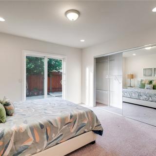 A modern and cozy bedroom featuring sliding doors, soft carpeting, and ample natural light.
