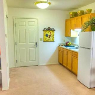 A small kitchen area with wooden cabinets and a white fridge next to a door.