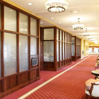 A well-lit hotel hallway featuring elegant wooden panels and a plush carpet.