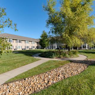 A peaceful courtyard with pathways, lush grass, and trees surrounding a building.
