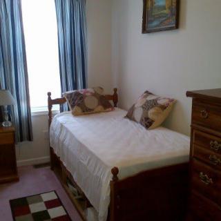 A cozy bedroom with a single bed, wooden furniture, and blue curtains.