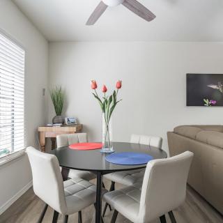A modern, minimalist dining area with a round table and chairs, decorated with tulips in a vase.