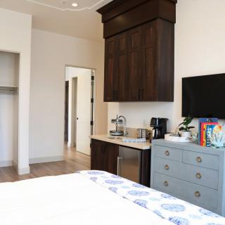 A modern bedroom featuring a TV, coffee maker, and dresser.