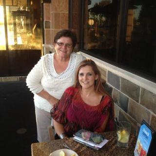 Two women smiling at an outdoor restaurant.