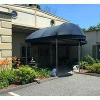 An entrance with a blue awning and landscaped surroundings.