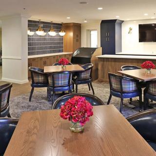 A modern dining area with wooden tables and chairs, decorated with red flowers.