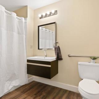 A modern bathroom featuring a floating sink, large mirror, and a shower with a white curtain.