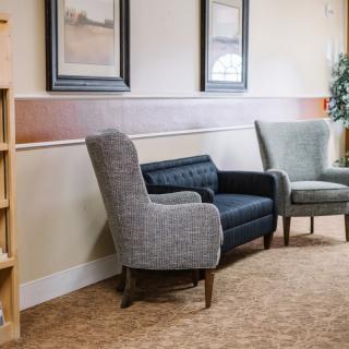 A cozy waiting room with comfortable chairs and framed artwork on the walls.