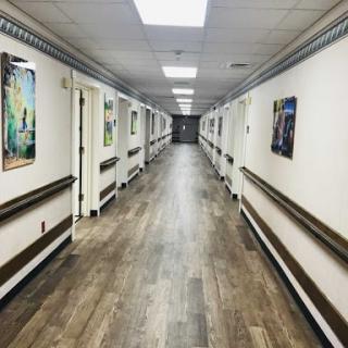 A long, well-lit hallway adorned with various pieces of artwork on the walls.