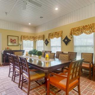 A cozy dining room with a long table, surrounded by chairs and adorned with decorative curtains and lighting.