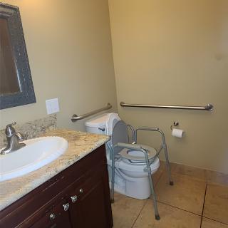 An accessible bathroom with a sink, toilet, and handrails.